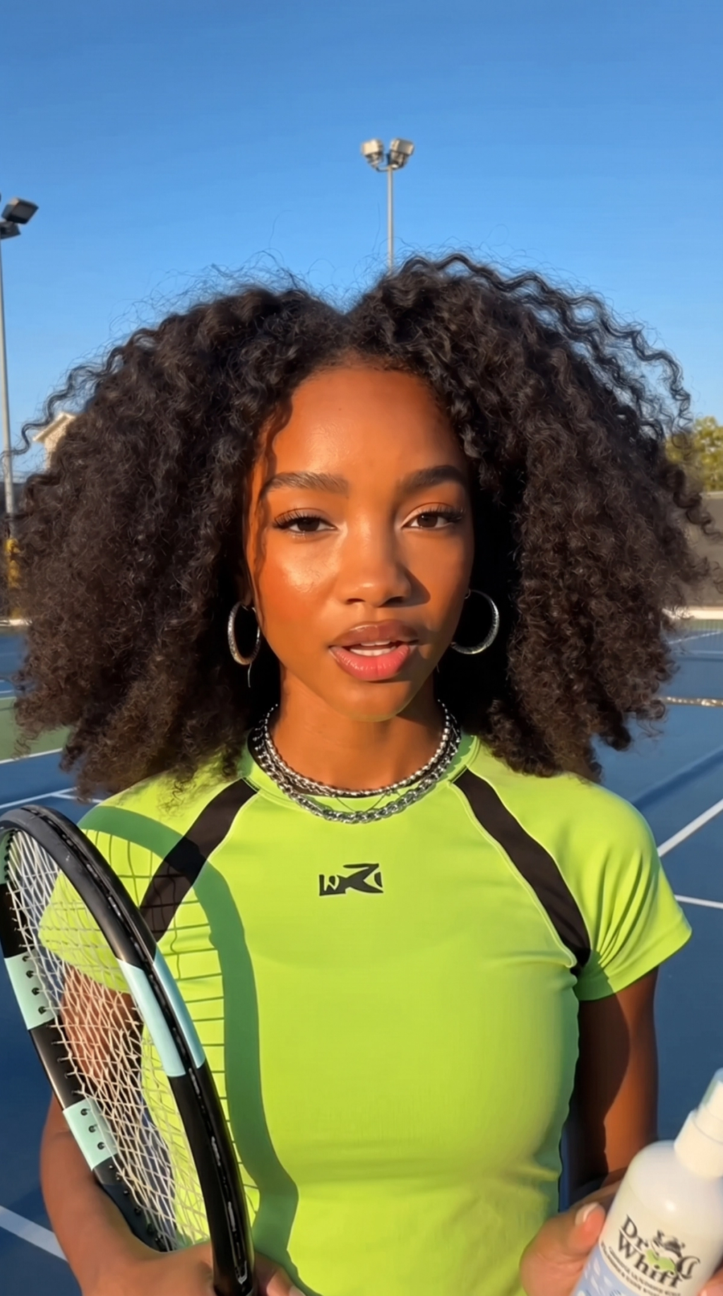 Tennis lifestyle creator reviewing Dr Whiff odor eliminator with tennis gear and athletic clothing in a home setting.
