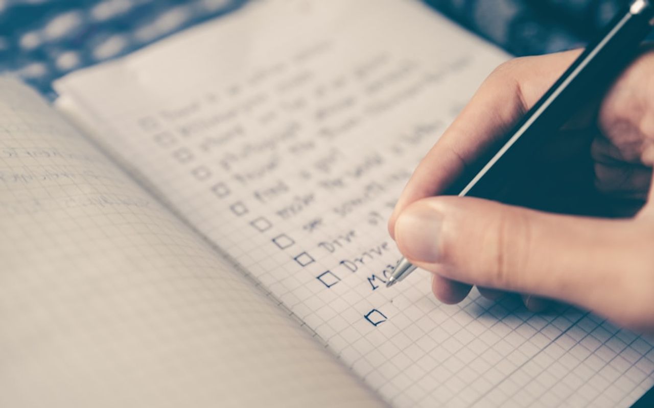 Checklist cochée sur un carnet posé sur un bureau avec un stylo