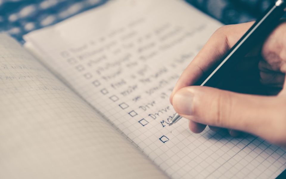Checklist cochée sur un carnet posé sur un bureau avec un stylo