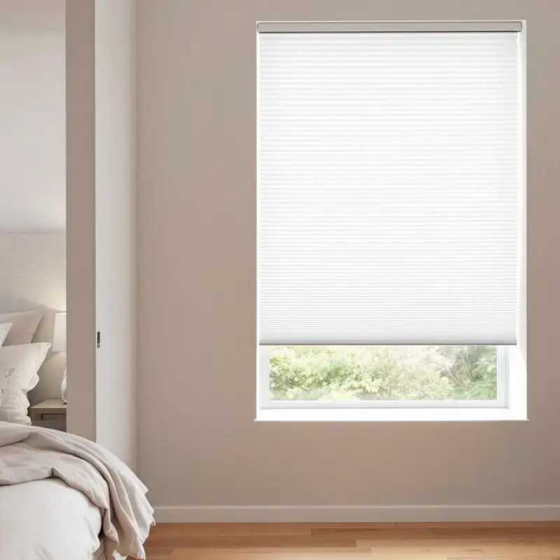 White cellular honeycomb blind fitted inside a bedroom window recess, soft morning light through the cells.