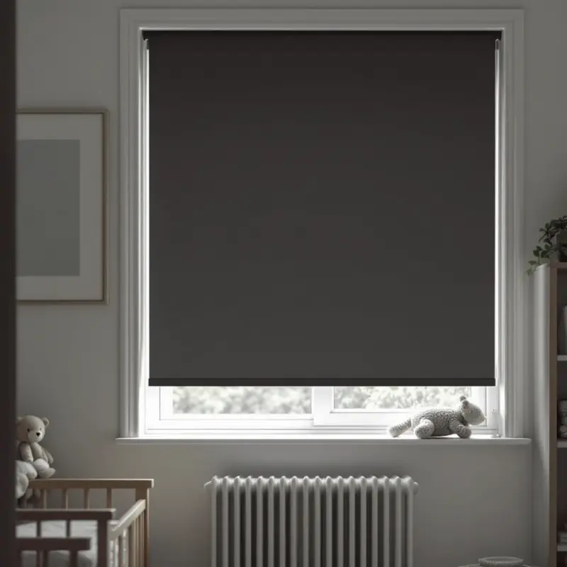 Charcoal blackout roller blind keeping a nursery dark for naptime, cot beside the window.