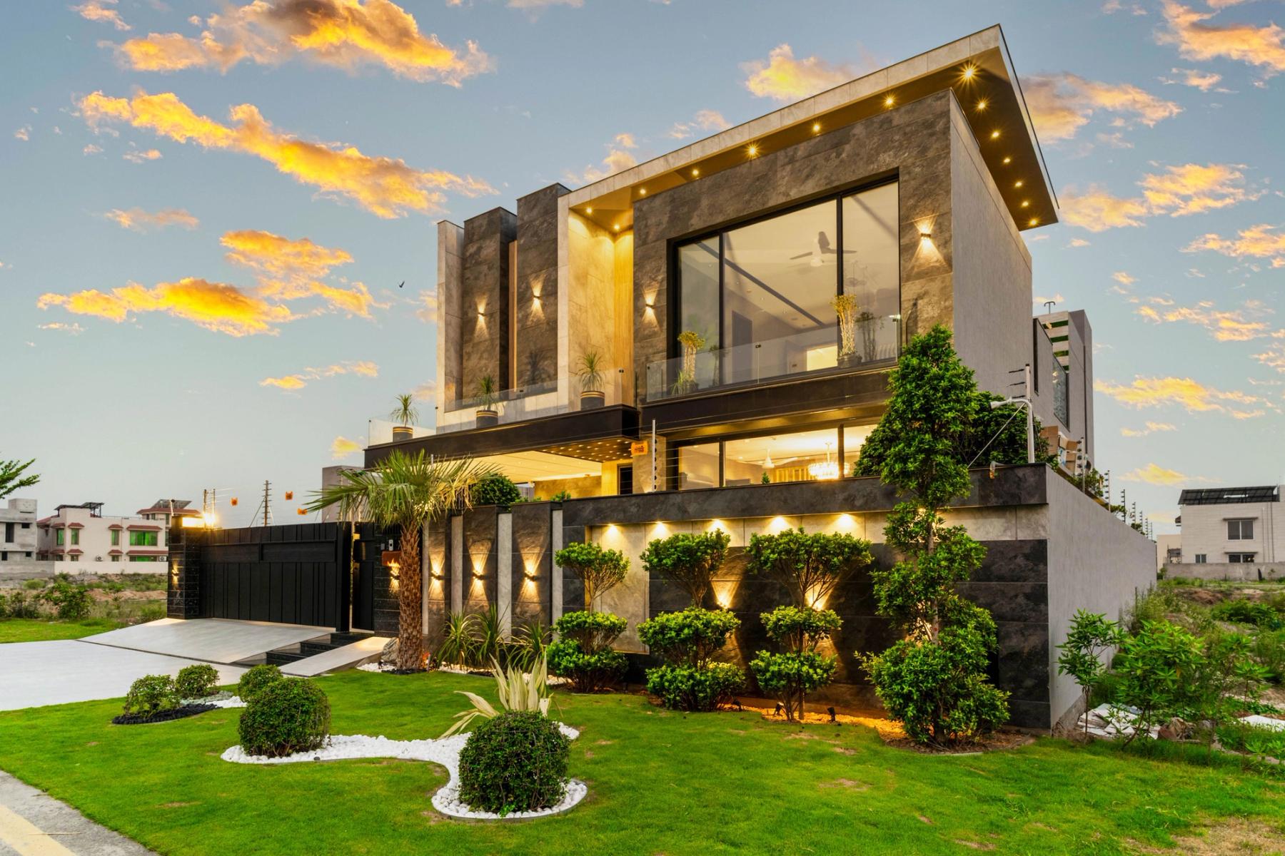 A stone-clad contemporary villa glowing at dusk, its stacked glass volumes above cascading planted terraces.