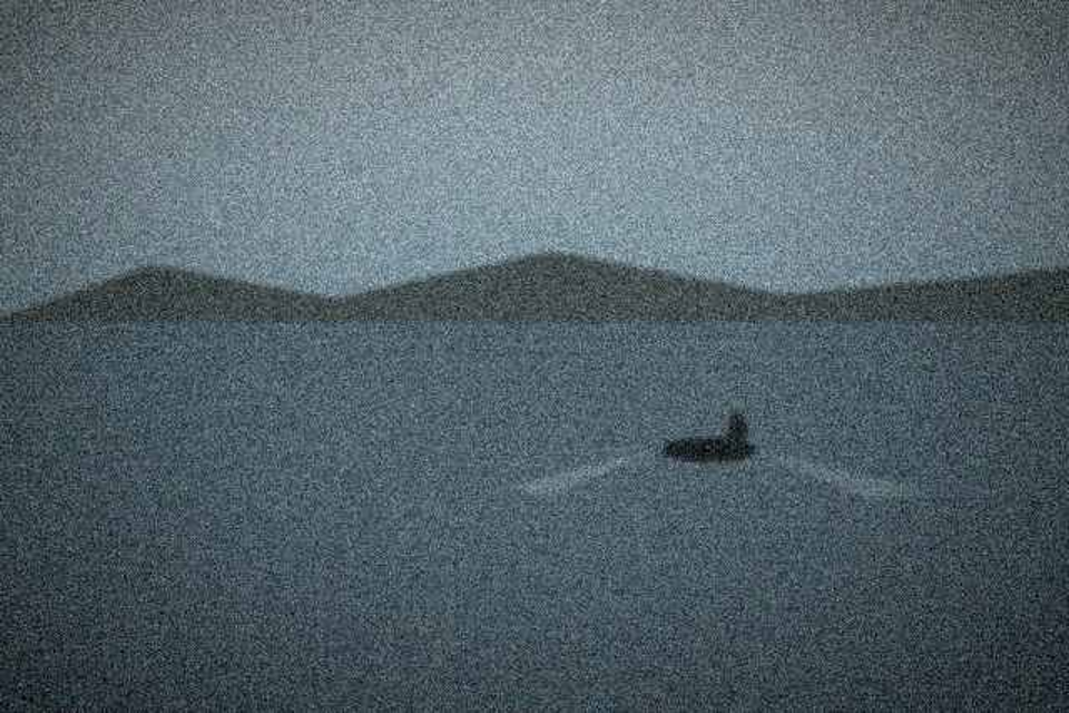 The shape, 420 metres out, a small dark mark on flat water