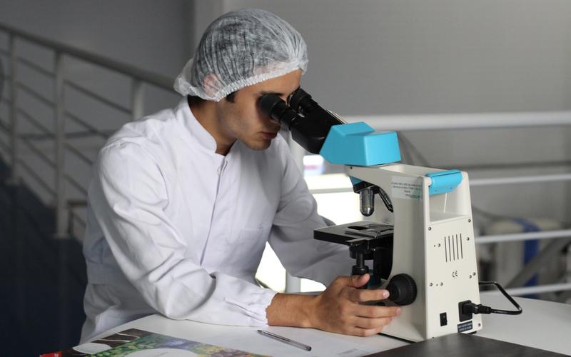 Mann im Labor an Mikroskop Restless-Legs-Syndrom