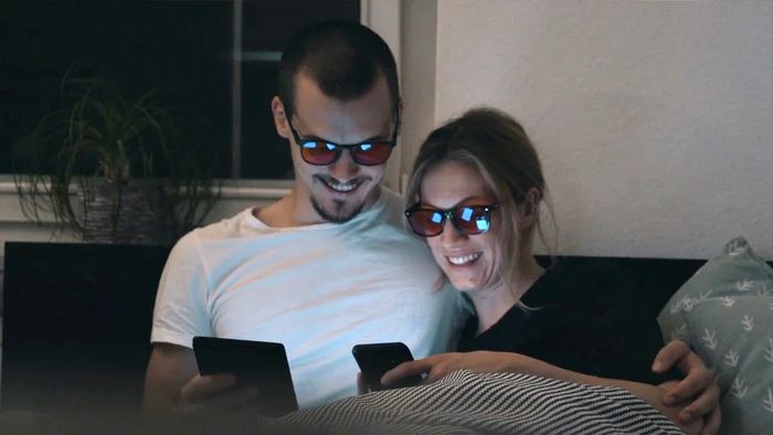 Paar auf Sofa mit Blaulichtfilterbrillen.