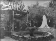 Crowd gathered near a covered monument and decorated ceremonial pavilion during a public event in a garden setting.