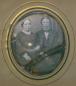 Daguerreotype portrait of man and woman in formal dress seated together, in ornate oval frame.