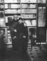 Vazha-Pshavela and David Kldiashvili posing indoors in front of shelves filled with books and documents.