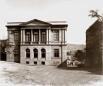 Black and white 19th-century photograph of the Caucasian Museum building on Golovin Avenue in Tiflis, showing a neoclassical two-story facade with arched windows.