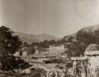 Historic black-and-white photograph of a Georgian mountain village with stone houses and several villagers in the foreground.