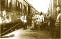 Historic photograph showing Sergo Ordzhonikidze walking with a group of uniformed and civilian men between two railway carriages at a station platform.