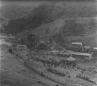 Large crowd gathered near a decorated railway tunnel entrance in a mountainous landscape.