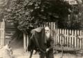 Elderly Vasil Roinashvili standing in a garden holding a camera under a cloth