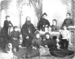 Studio portrait of a Georgian Orthodox priest seated with members of his family, surrounded by several children.