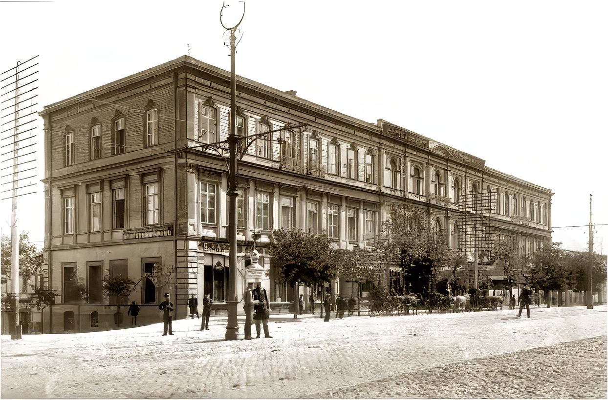 Two-storey 19th-century hotel building on Glovin Avenue in Tbilisi with pedestrians and street activity in front.