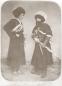 Two men in traditional Caucasian dress with fur hats, long robes, cartridge belts, and weapons, posed in a studio setting.