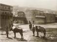 Two water carriers with donkeys transporting leather water bags on the bank of the Mtkvari River in Old Tbilisi.