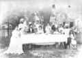 Outdoor photograph of the Georgian aristocratic Tumanishvili family gathered around a table with a samovar and tea service, accompanied by children and attendants.