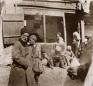 Photograph showing several men and boys gathered and sitting in front of a shop or stall in the Tiflis bazaar, late 19th century.
