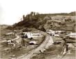 Historic photograph showing a road passing through Surami Pass with houses and hills in the landscape.