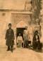 Men standing and sitting at the entrance of the Tiflis sulfur baths, in front of a decorated architectural doorway.