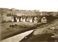 Stone arch bridge known as Mikhail’s Bridge crossing the Mtkvari River in Tbilisi with horse-drawn carts nearby.