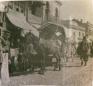 Horse-drawn cart standing on a cobbled street with several people nearby in a market district of Tiflis.