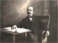 Studio portrait of Georgian scientist Aleksandre Didebulidze seated at a desk with papers.