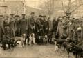 Group of hunters standing with hunting dogs, posed outdoors.