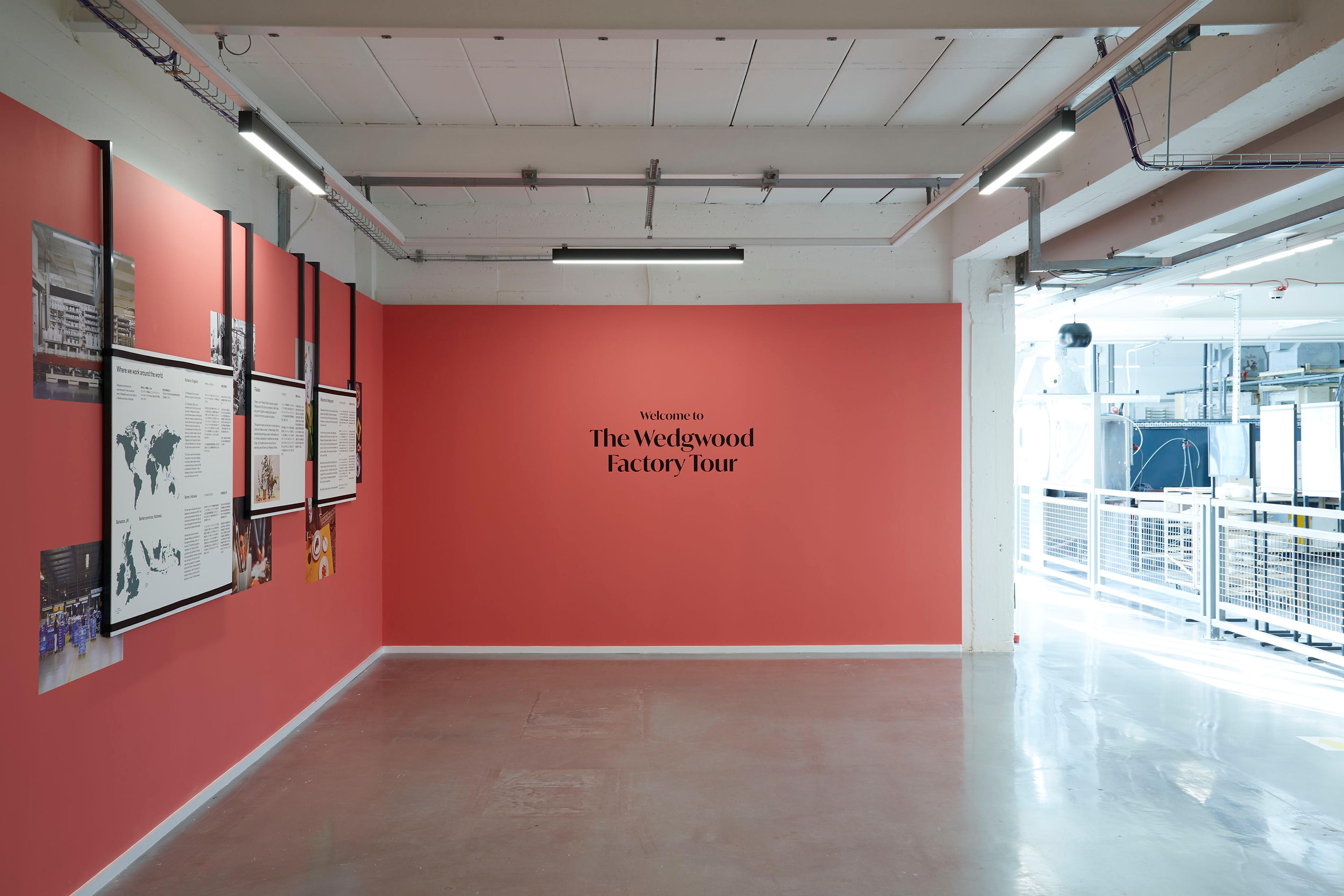Factory introduction space, title vinyl on red wall and text panels mounted on frames hanging from the ceiling