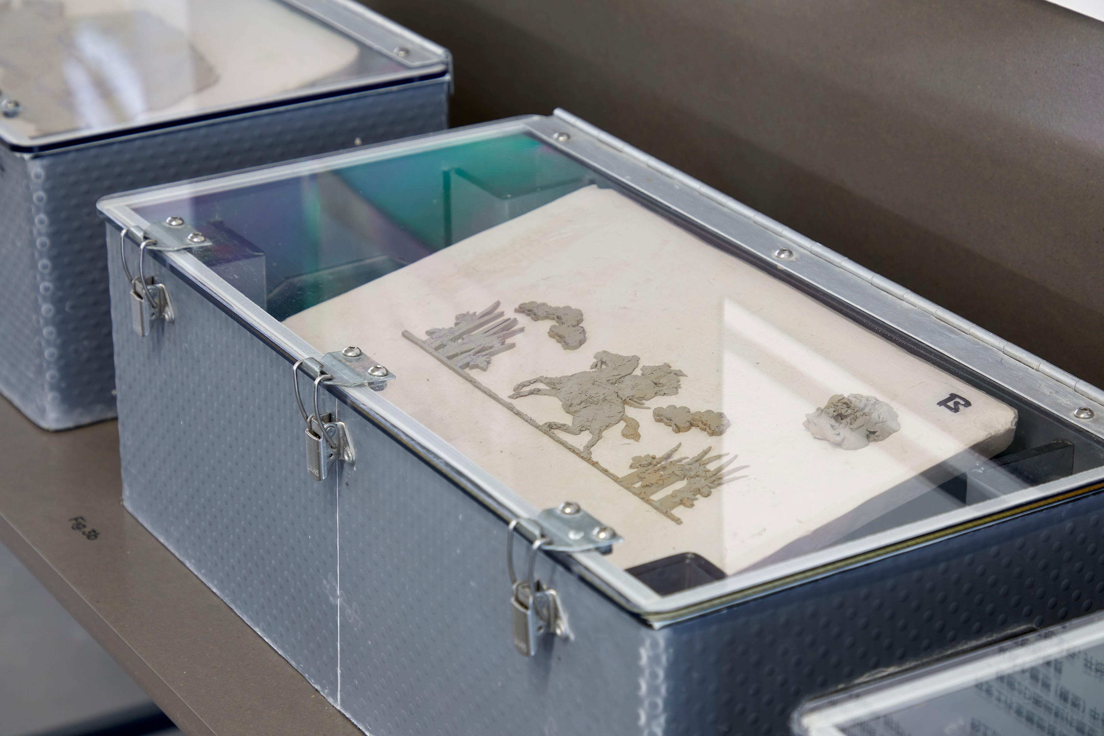 Box with clear perspex lid showing the process of creating reliefs to be applied to ceramic products.