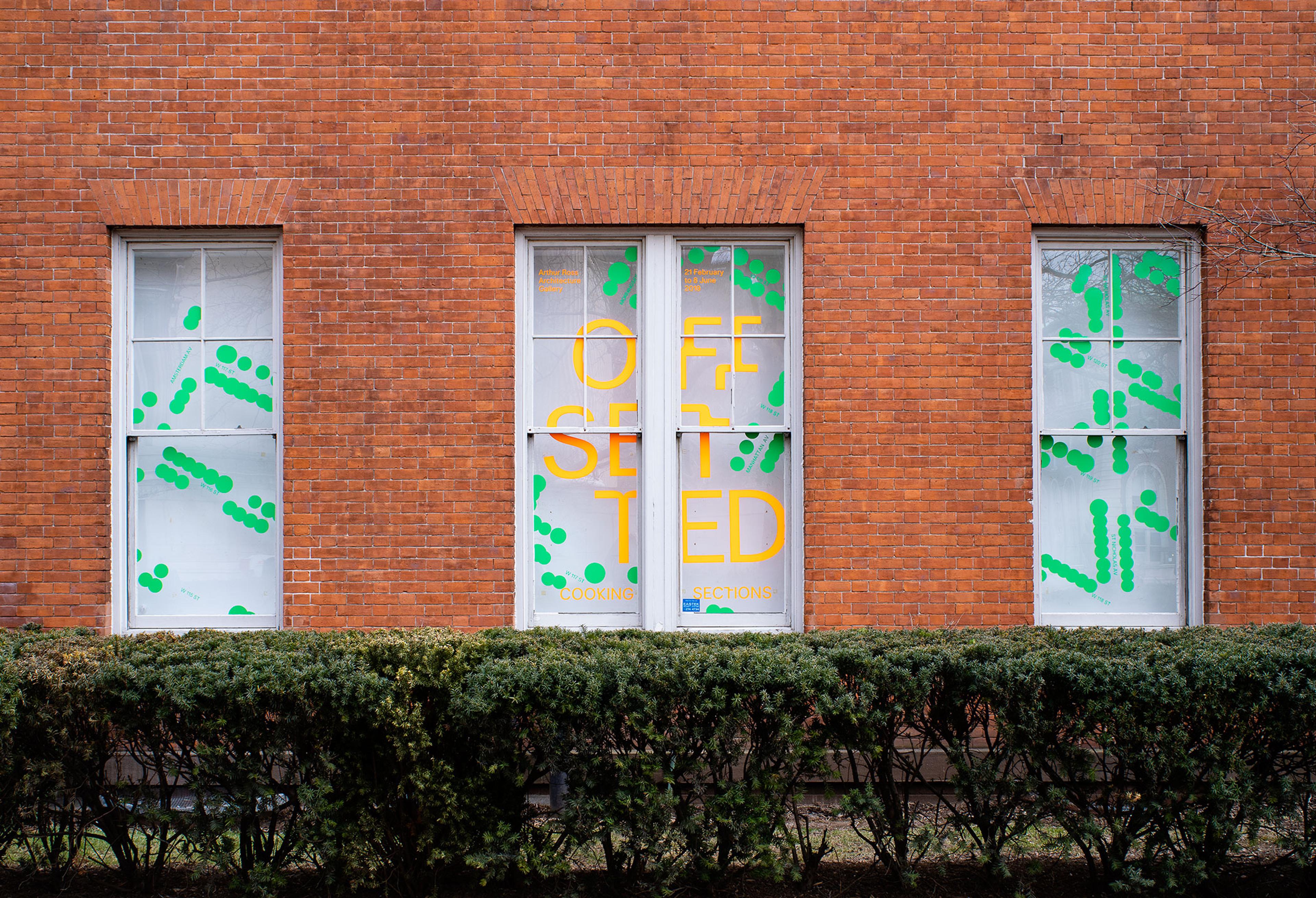 Photograph of window vinyl on exterior of gallery. 'Offsetted' is in fluorescent orange cut vinyl and surrounded by green cut vinyl dots.