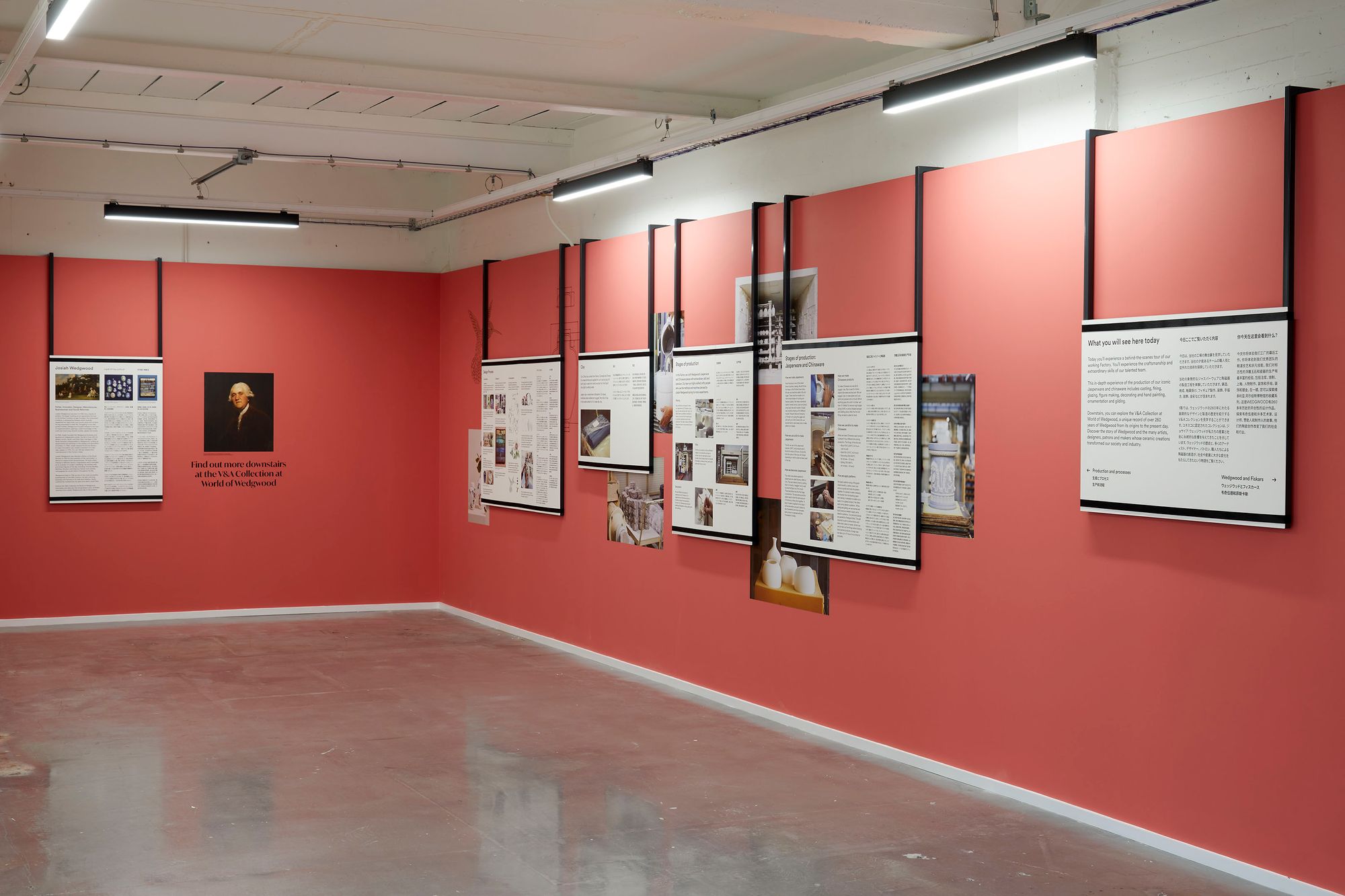Second angle of introductory space showing more hanging text panels on red wall