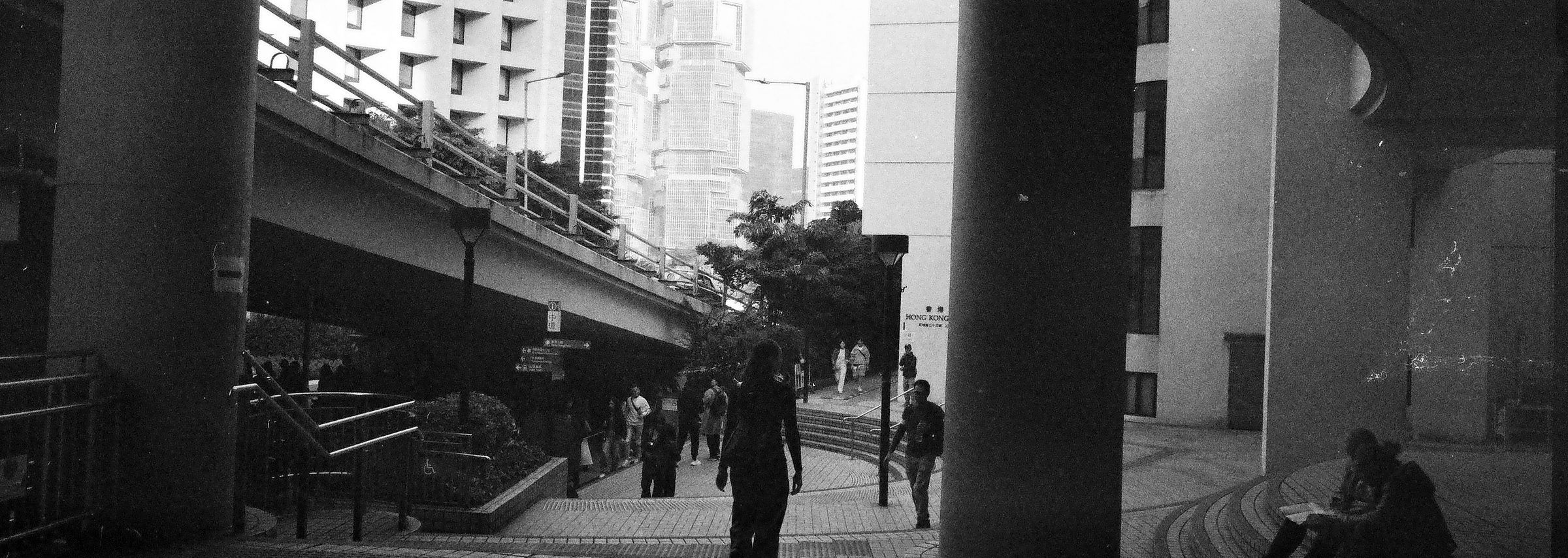 Pedestrians walking beneath a flyover between concrete columns