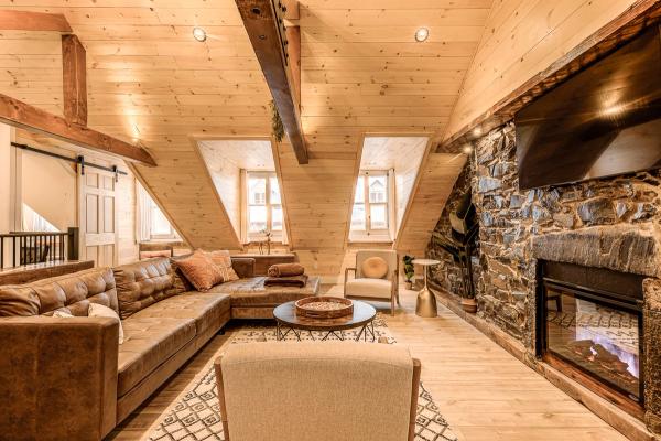 Living room with stone fireplace, lofted exposed beam ceiling and large couch
