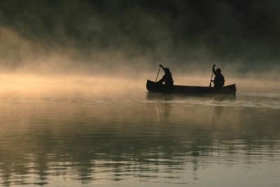 Two people canoeing in the early morning mist