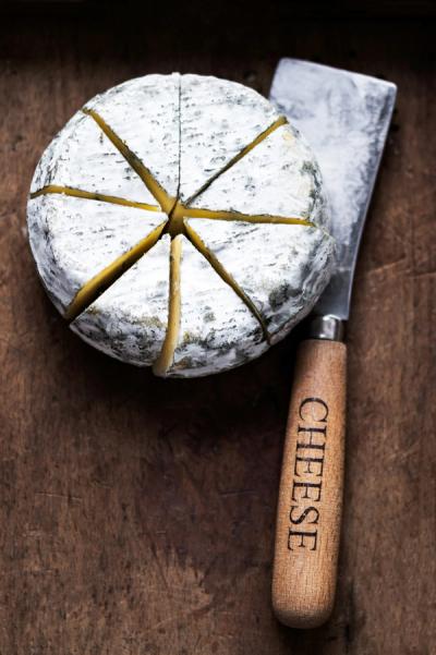 Wheel of cheese on a board with a knife