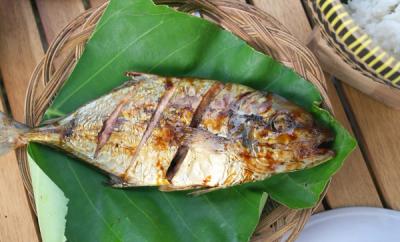 Fried fish on a leaf on a wooden table