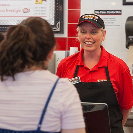 Firehouse subs coworker smiling while taking an order from a customer