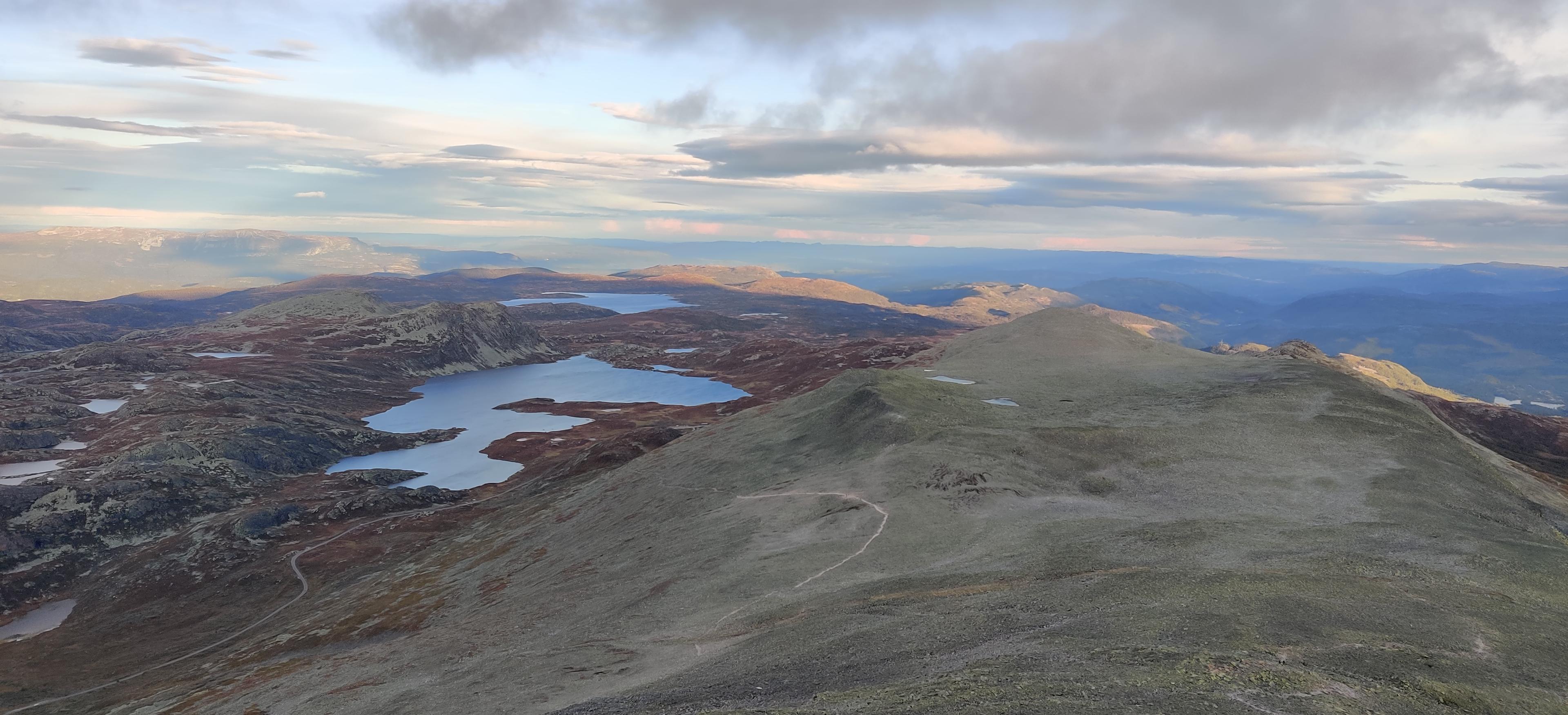 a group of people are sitting around a fire near a lake