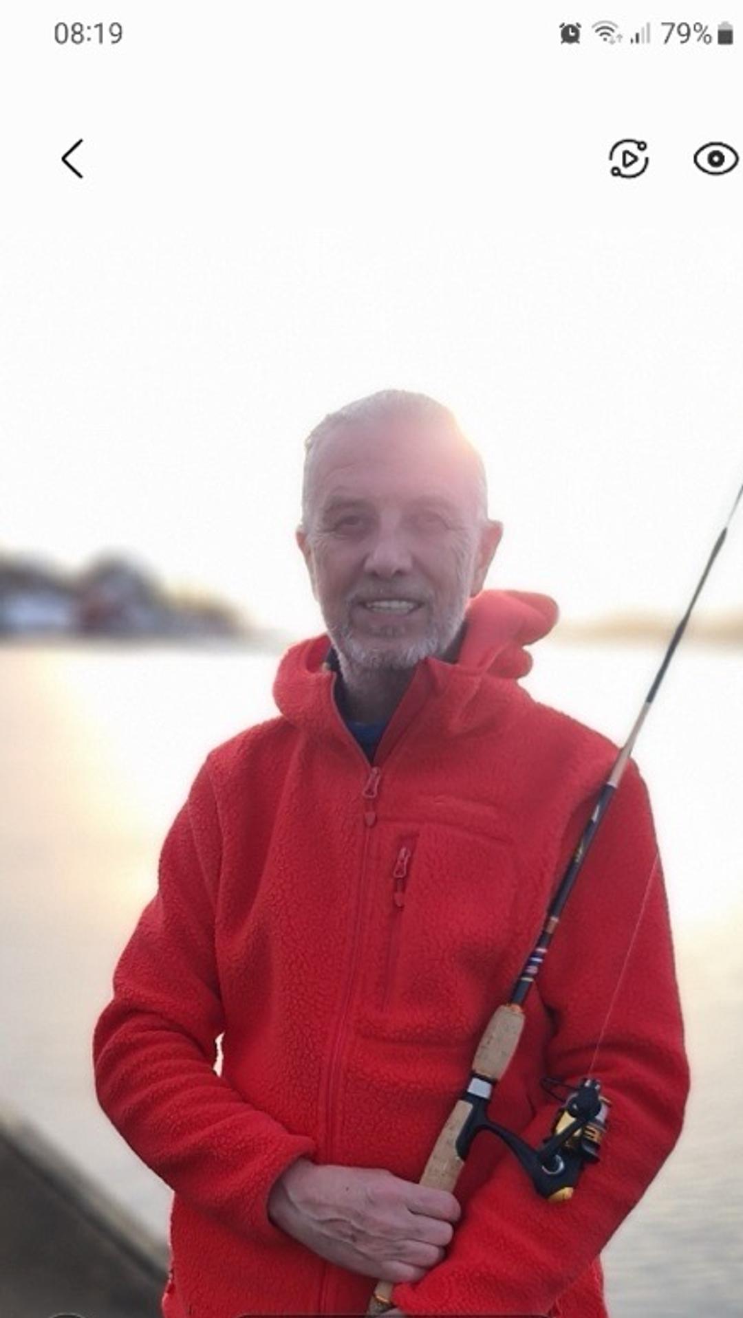 a man in a red jacket is holding a fishing rod