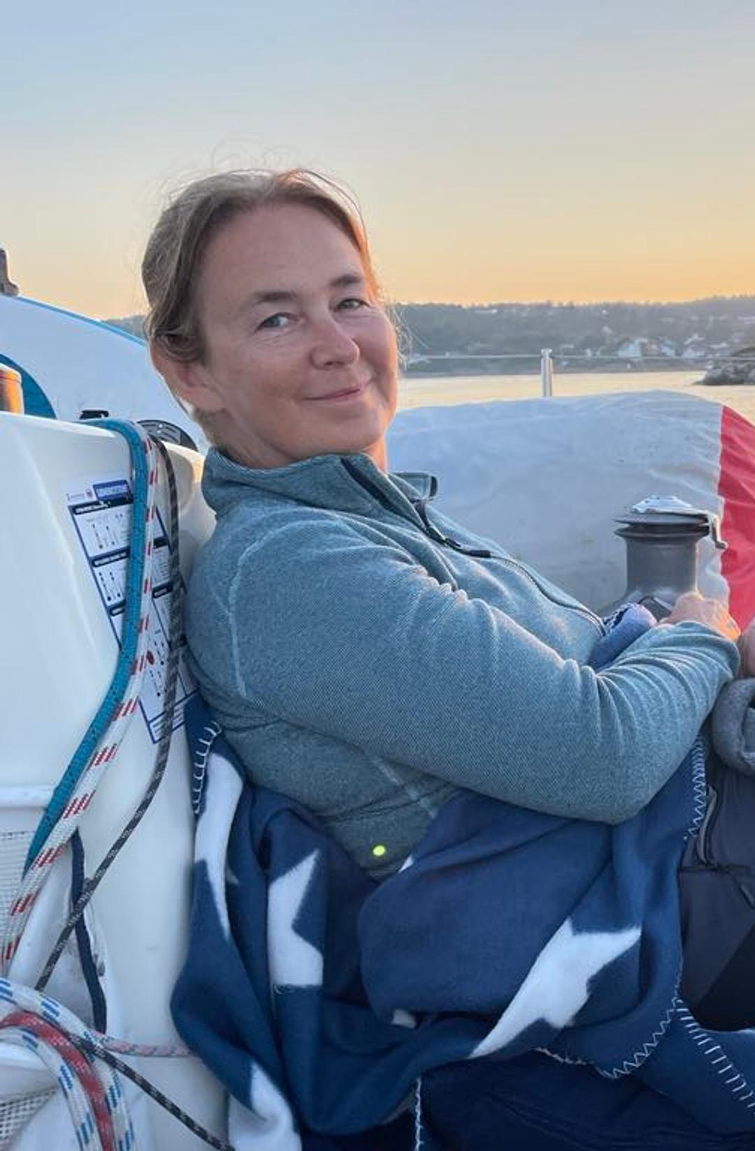 a woman is sitting on a boat covered in a blanket .