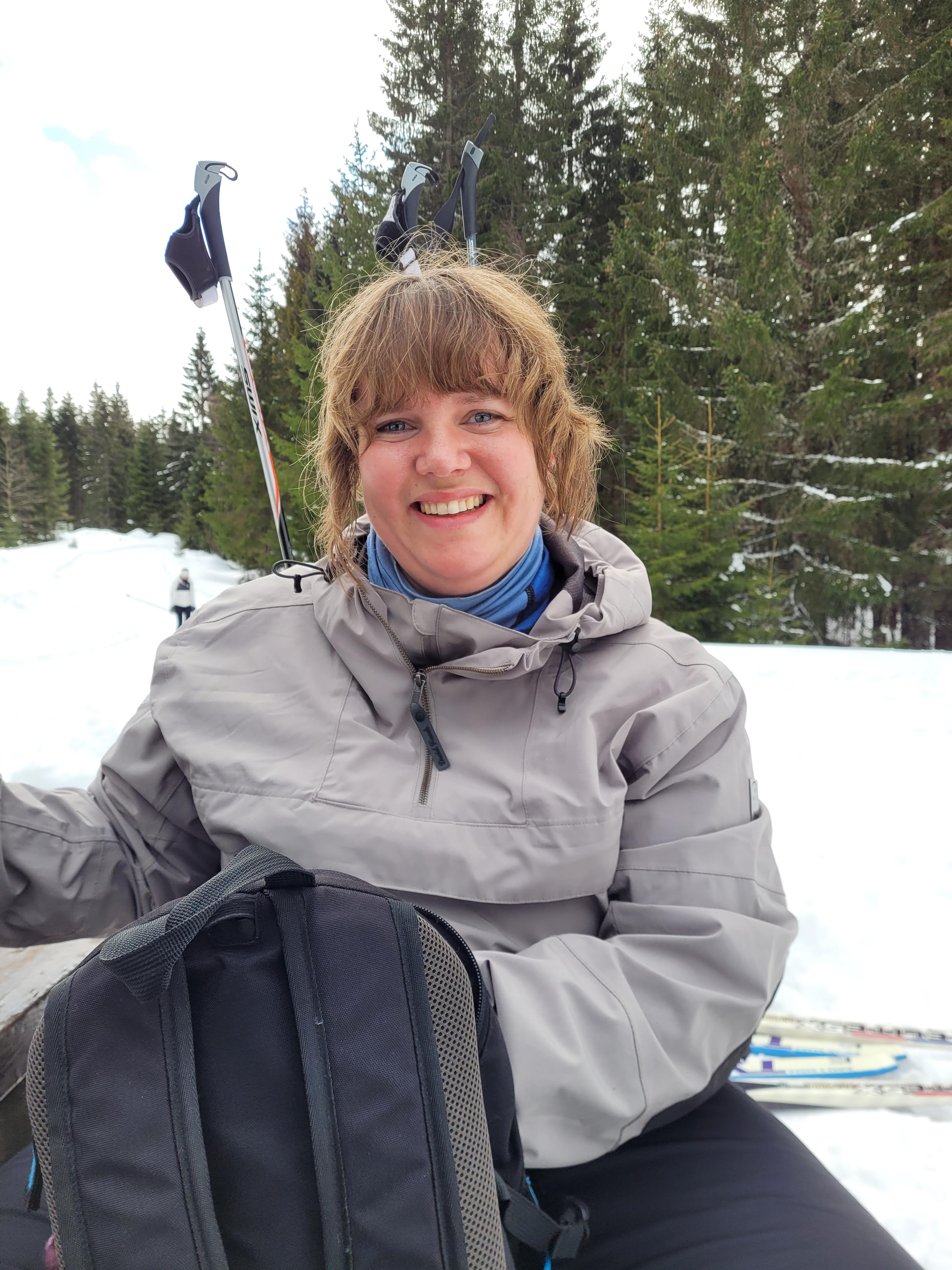 a woman sitting in the snow with skis and a backpack