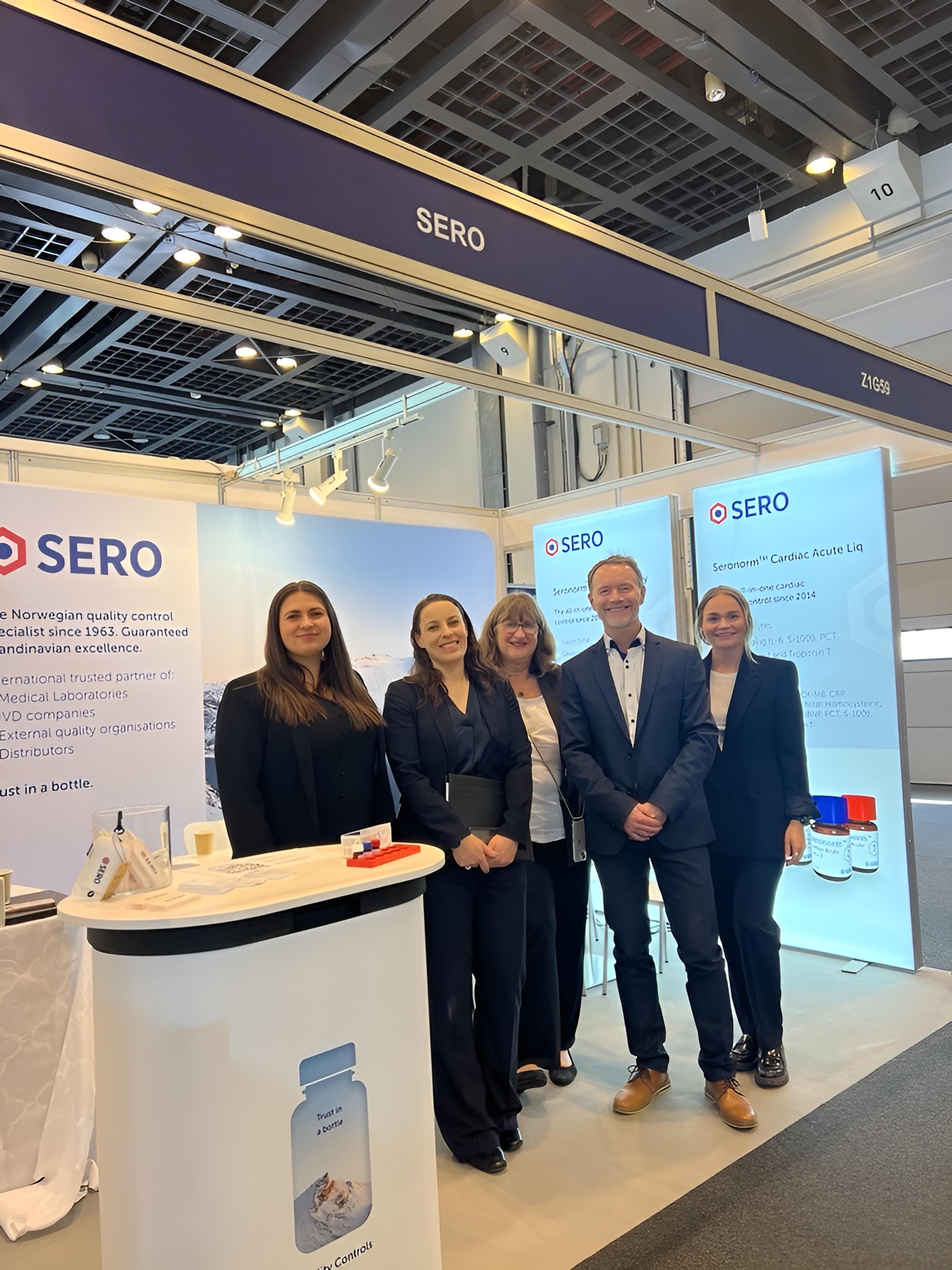 a group of people standing in front of a sign that says sero