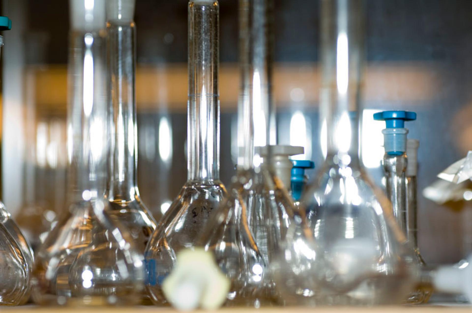 a bunch of empty beakers are sitting on a shelf in a lab.