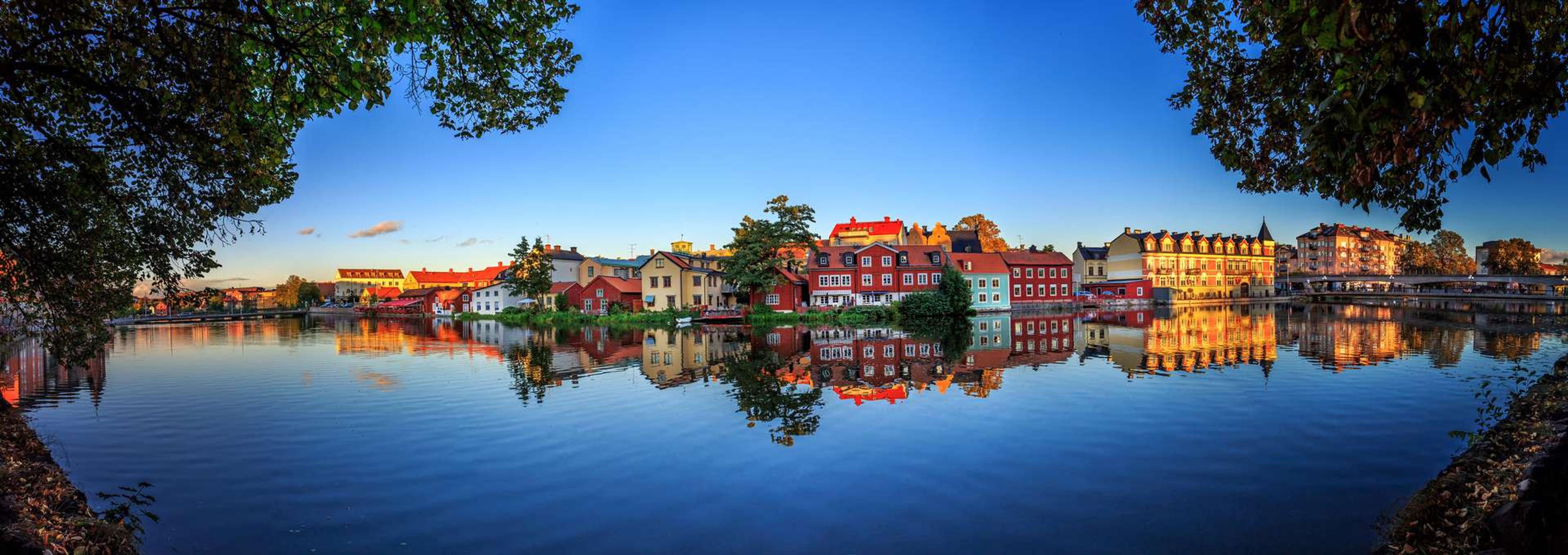 a panoramic view of a city along a lake at sunset . vårmøte klinisk kjemi eskilstuna