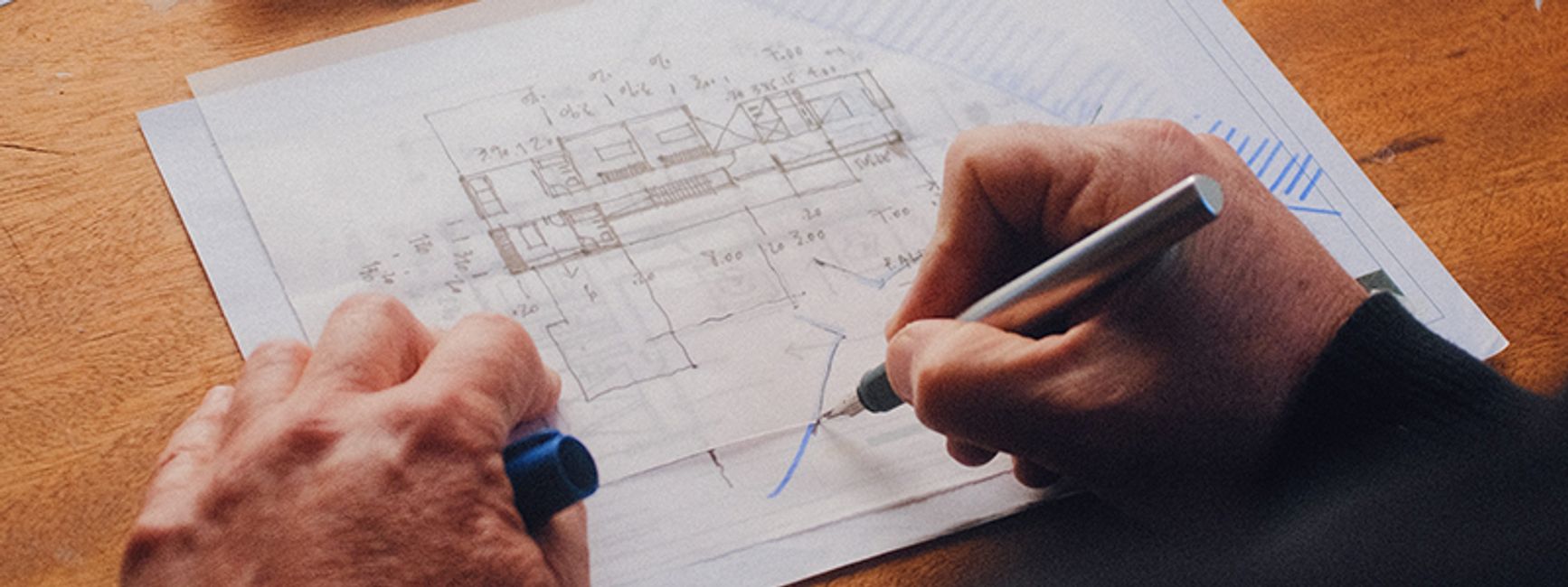 A photograph of a man's hands doing a technical drawing.