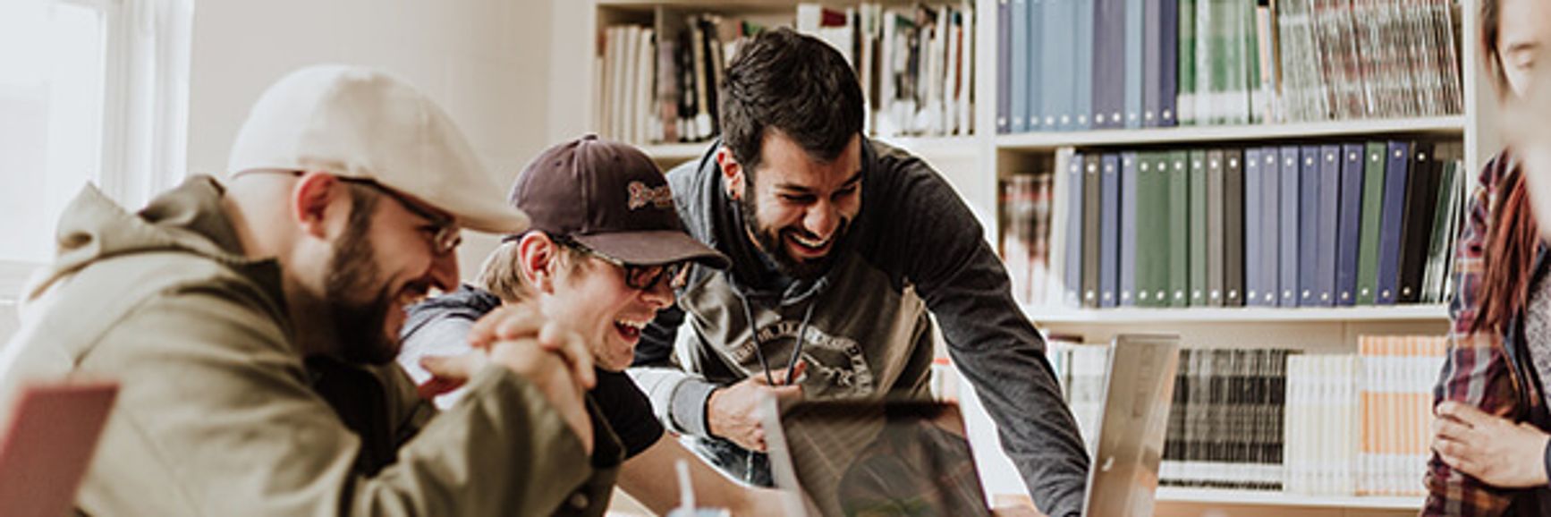 A photo of a creative team laughing as they all look at one computer screen.