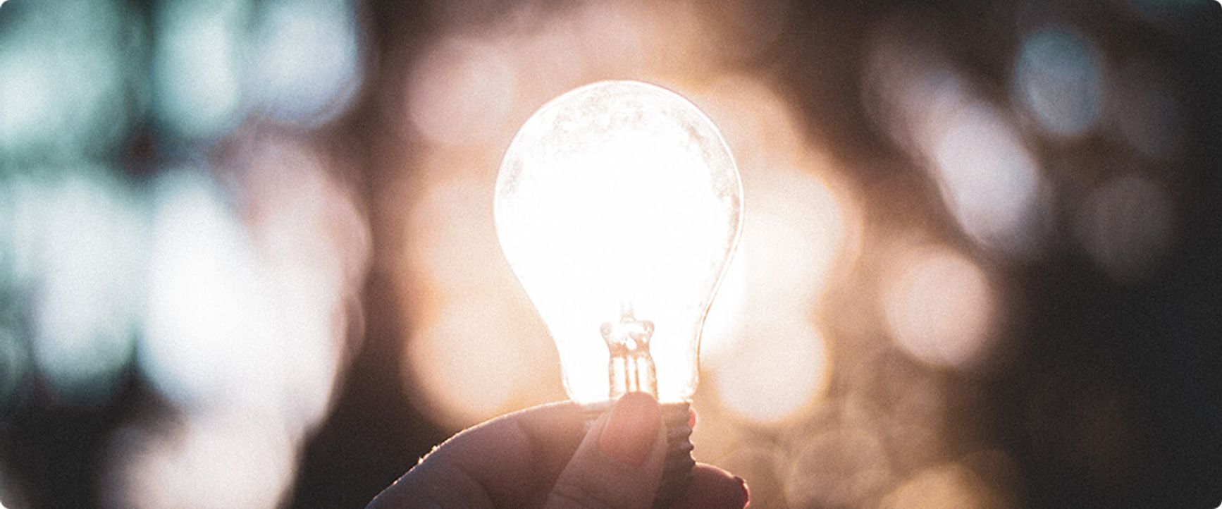 A lightbulb glowing in someone's hand.