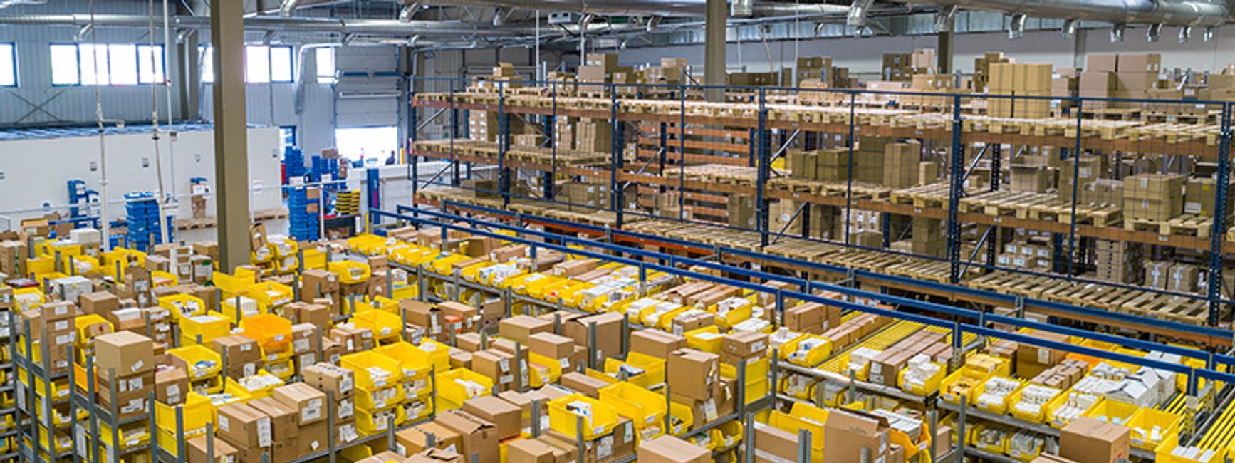A photo of a busy warehouse with tall shelves full of boxes.